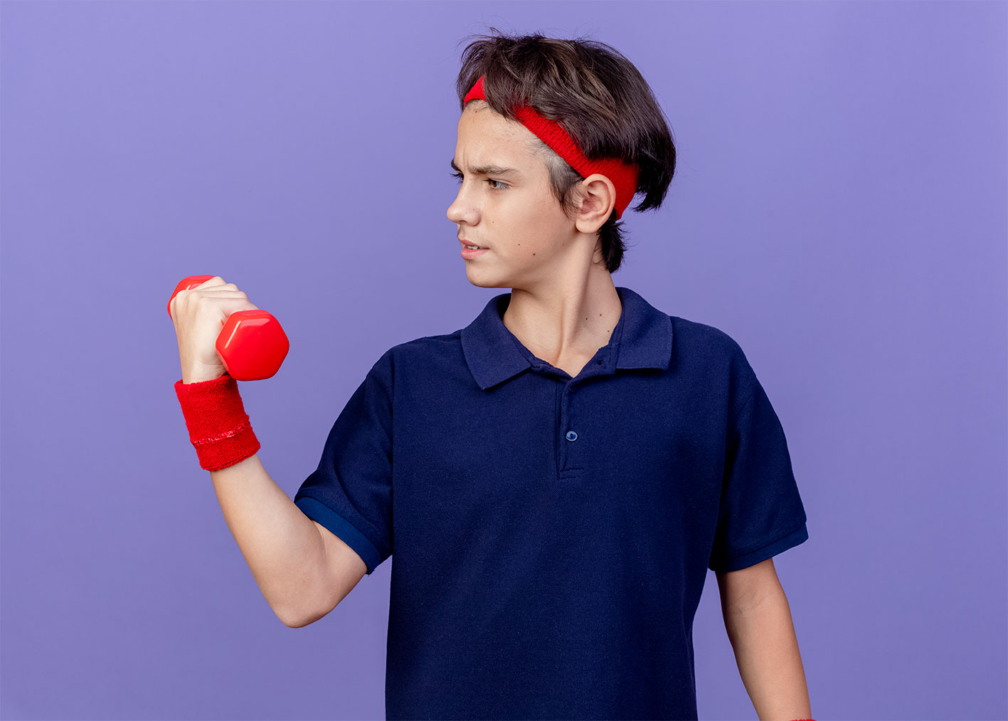 Young boy wearing a sweatband and holding a dumbbell in his right hand doing a bicep curl