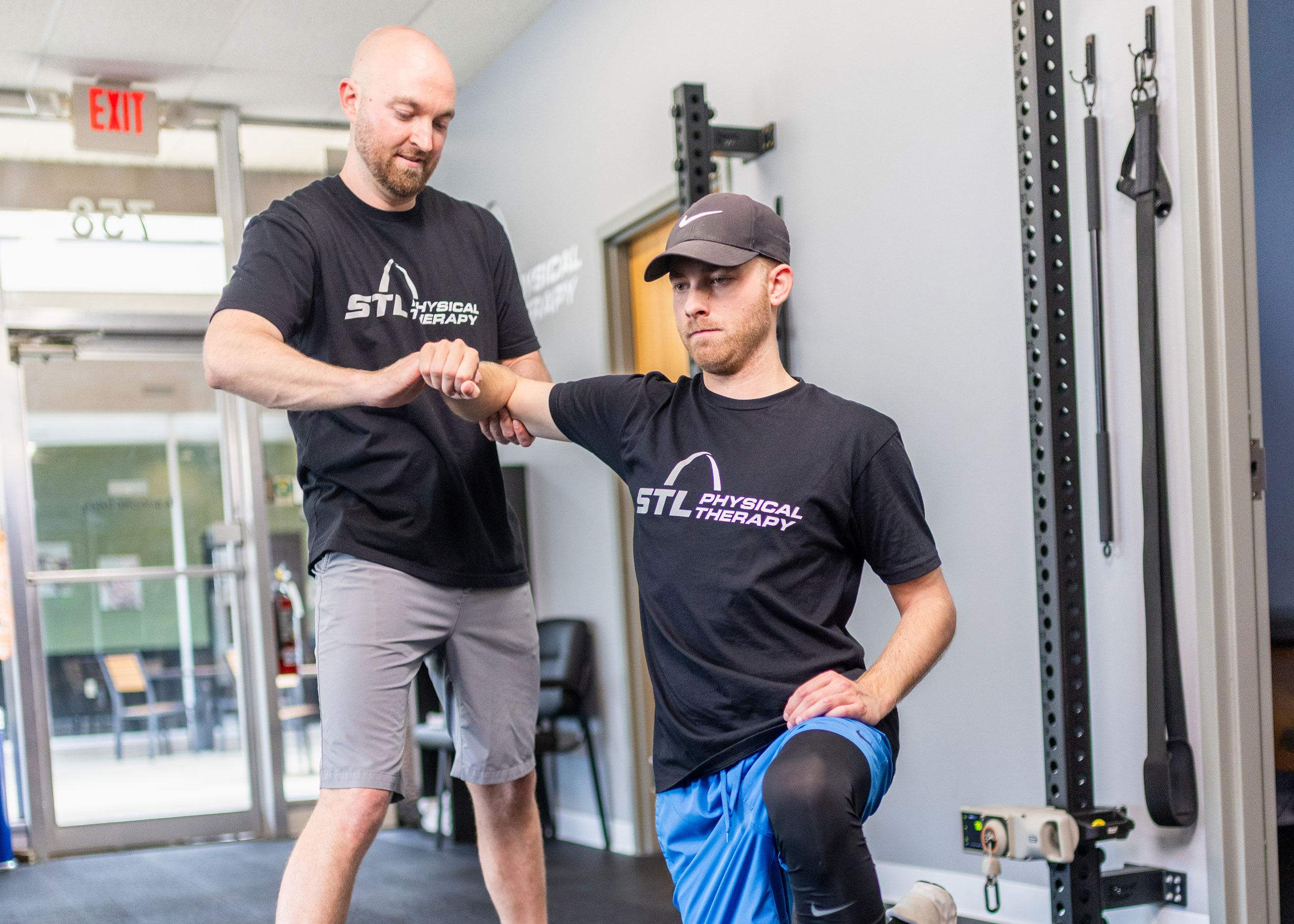 STL PT trainer working with a male patient on arm exercises within the clinic training room